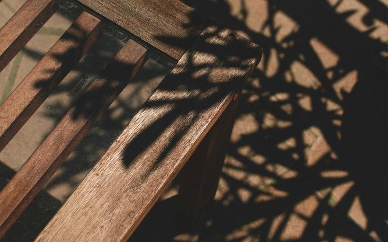 a wooden chair with shadows of leaves